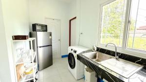 a kitchen with a washer and a sink and a refrigerator at Temple Light in Ko Phangan