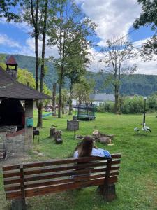 a woman sitting on a bench in a park at Готель in Yaremche