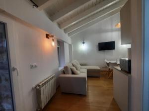 a white living room with a couch and a tv at SEL apartamentos rurales in Sel de la Carrera