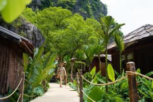 a child walking down a path in front of houses at Karsia Retreat Ninh Binh in Ninh Binh