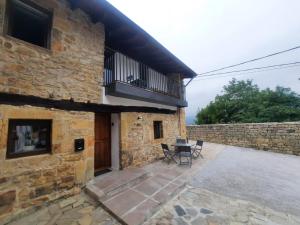 a stone house with a patio and a balcony at SEL apartamentos rurales in Sel de la Carrera