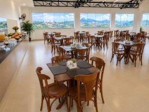 a dining room with tables and chairs and windows at Hotel Vista Bela in Itamaraju