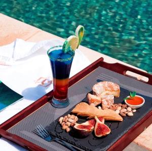 a tray of food and a drink next to a pool at Centre Touristique Le Sable in Alger
