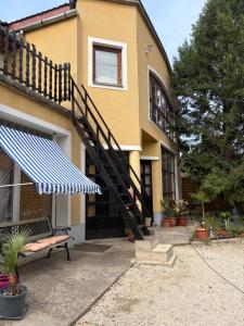 a house with a staircase and a bench in front of it at Villa Lavanda Vendégház & Spa in Gyulakeszi
