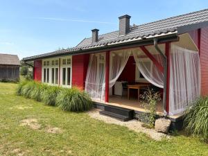 a red house with a deck and a table at Leśne Doliny 38 in Zwiartów
