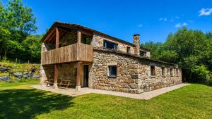an old stone house with a balcony on a lawn at Las Hayucas in San Roque de Ríomiera
