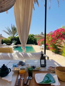 a table with food on it next to a pool at Dar Alya Essaouira Maison et table d'hôtes in Ghazoua