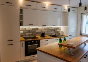 una cocina con armarios blancos y una mesa de madera en Rezydencja PPPR, 