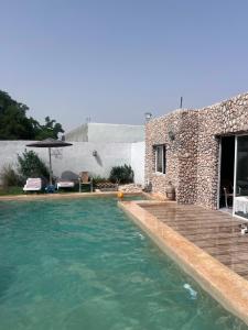a swimming pool in front of a stone house at Villa compagne sans vis-à-vis in Ounara