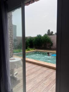 a person in a swimming pool through a sliding glass door at Villa compagne sans vis-à-vis in Ounara