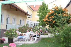 イルミッツにあるPension & Weingut Storchenblickの庭園のテーブルに座る人々