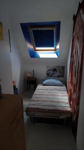 a small bedroom with a bed with a skylight at Sterne pierregarin 2kms de la plage in Séné