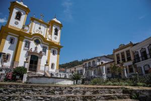 a yellow and white building with a clock tower at Sobiuai 72 in Ouro Preto