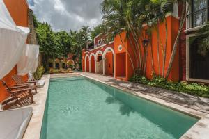 an orange building with a swimming pool next to a house at Casa Jade Hotel - Adults Only, Mérida in Mérida