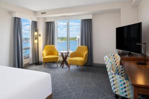 a hotel room with a bed and a television and chairs at Hampton Inn by Hilton Halifax Downtown in Halifax