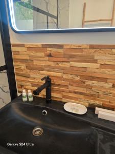 a black sink in a bathroom with a wooden wall at La lézarde in Cavalaire-sur-Mer