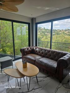 a brown leather couch in a room with windows at La lézarde in Cavalaire-sur-Mer