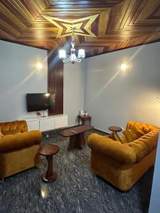 a living room with two couches and a tv at Fokam Hôtel in Nkongoa