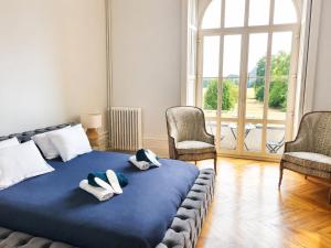a bedroom with a bed and two chairs and a window at Château de Savonnières in La Bruère-sur-Loir