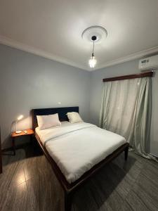 a bedroom with a large bed with white sheets and a window at Fokam Hôtel in Nkongoa