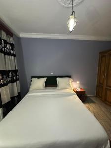 a large white bed in a room with a lamp at Fokam Hôtel in Nkongoa