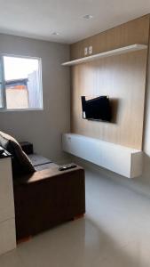 a living room with a couch and a tv on the wall at Flat Eufrates 205 in Olinda
