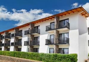 a white apartment building with balconies on it at Sierralta Hotel Cabañas y Convenciones in Mazamitla