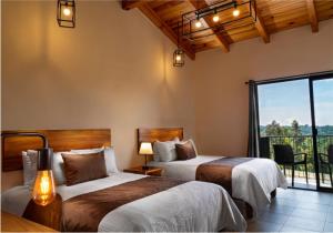 a bedroom with two beds and a large window at Sierralta Hotel Cabañas y Convenciones in Mazamitla +39 photos