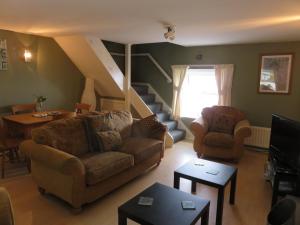 a living room with a couch and a staircase at The Coach House Self Catering Apartments in Glenariff