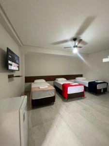 a room with three beds and a ceiling fan at Neves Hotel II in Ipatinga
