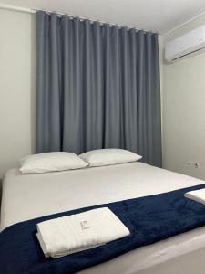 a bedroom with a bed with a blue curtain at Neves Hotel II in Ipatinga