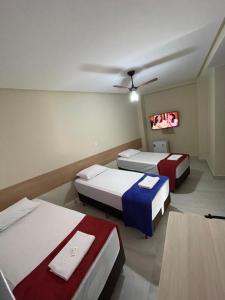 a room with two beds and a tv at Neves Hotel II in Ipatinga +4 photos