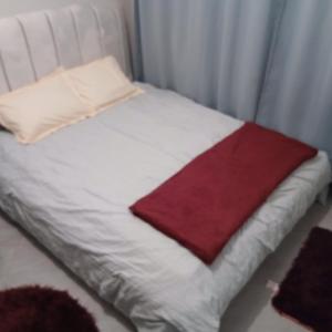 a small white bed with a red blanket on it at Studio apartment at Arc Residence in Nairobi