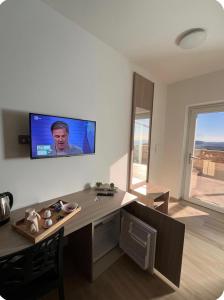 ein Wohnzimmer mit Schreibtisch und Fernseher an der Wand in der Unterkunft La Terrazza in Cotronei