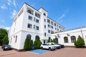 ein weißes Gebäude mit auf einem Parkplatz abgestellten Autos in der Unterkunft Grand Hotel Orient Braila in Brăila