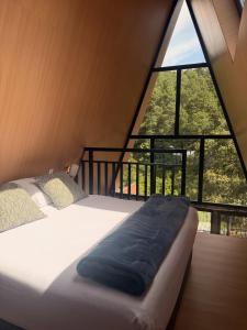 a bed in a room with a large window at La Estela NatureSuite in Mazamitla
