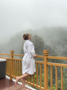 a woman in a white dress walking on a fence at La Estela NatureSuite in Mazamitla