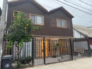 a house with a black fence and a tree at Arriendo habitaciones Talca in Talca