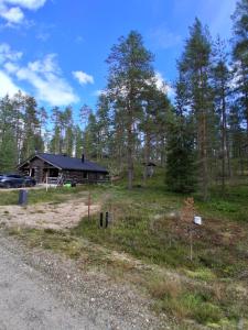 a cabin in the woods next to a gravel road at Iso-Syöte tunnelmallinen kelomökki in Naamanka +8 photos