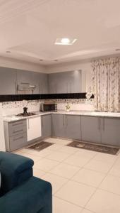 a kitchen with white cabinets and a blue couch at Maisons Maktoub Djerba in Al Maqārisah