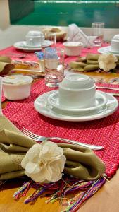 a table with a red table cloth with plates and napkins at Pousada Jara in Conservatória