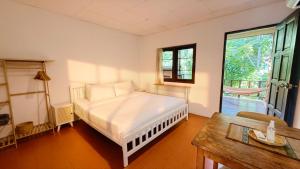 a bedroom with a bed and a table and a window at Zen Hideaway - Cute Modern Thai Home in Ko Phangan