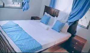 a bed with blue and white sheets and pillows at Ryma Airbnbs in Mombasa