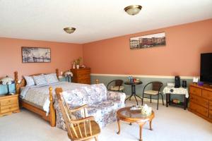 a bedroom with a bed and a couch and a table at The Shearwater House - Panoramic Ocean View Suites in Nanaimo