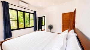a bedroom with a large bed and two windows at Zen Nest in Ko Phangan