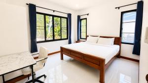 a bedroom with a bed and a desk and windows at Zen Nest in Ko Phangan