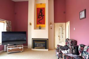 a living room with a tv and a fireplace at The Shearwater House - Panoramic Ocean View Suites in Nanaimo +11 photos