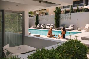 two women sitting next to a swimming pool at Brasil Suites Boutique Hotel in Athens