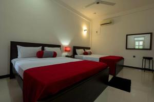 a hotel room with two beds with red sheets at My Home Guest in Polonnaruwa
