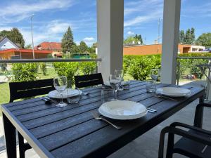 a wooden table with plates and wine glasses on it at Oliva Apartman in Bük